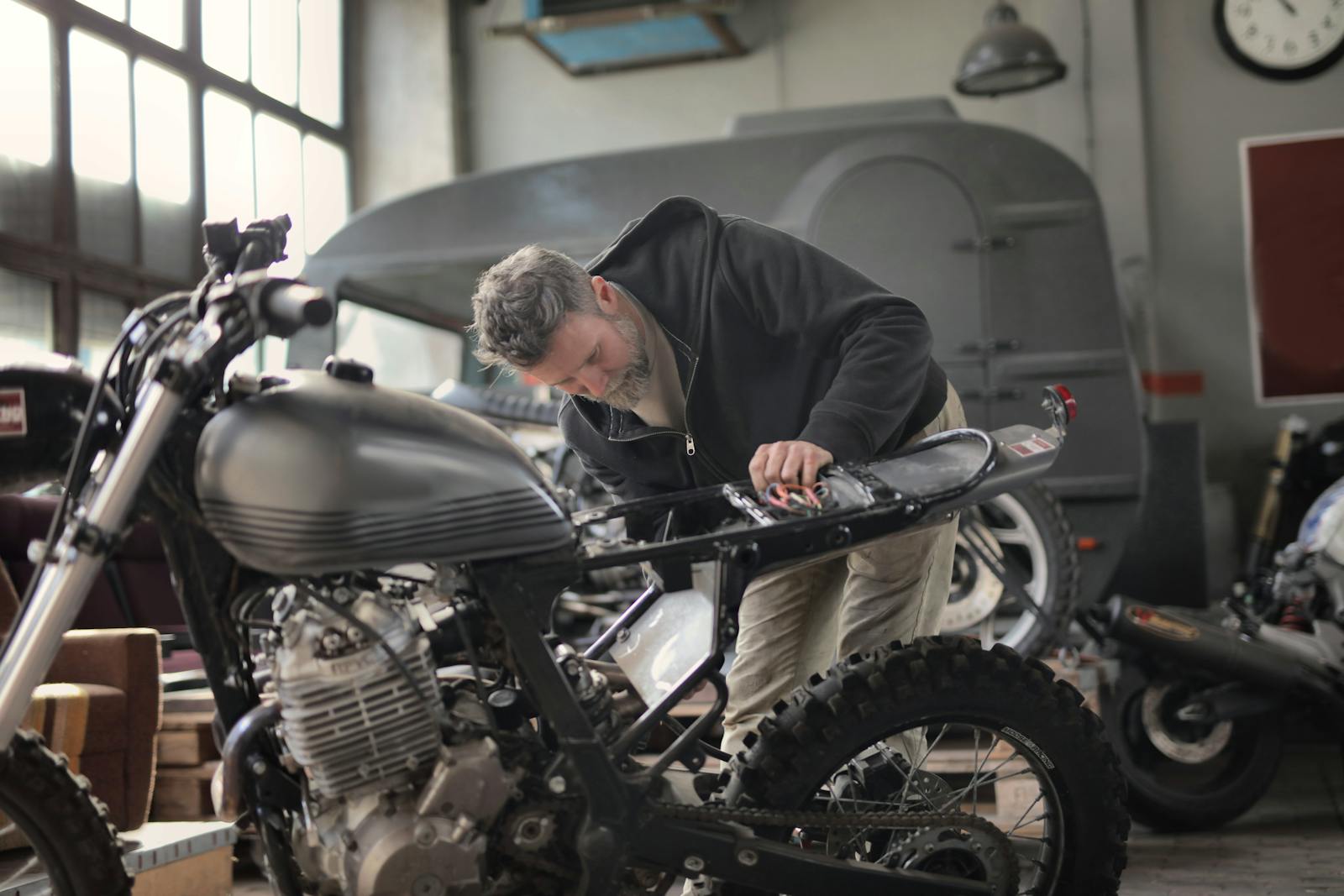 Man in Black Jacket Inspecting a Motorcycle